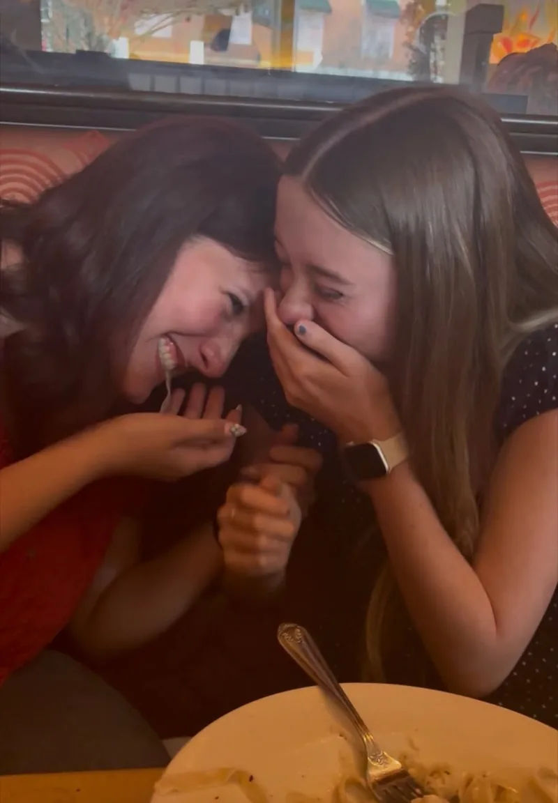 Two friends laughing together at dinner